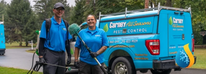 Two pest control technicians standing with sprayer equipment in front of a Carney All Seasons Pest Control service truck.